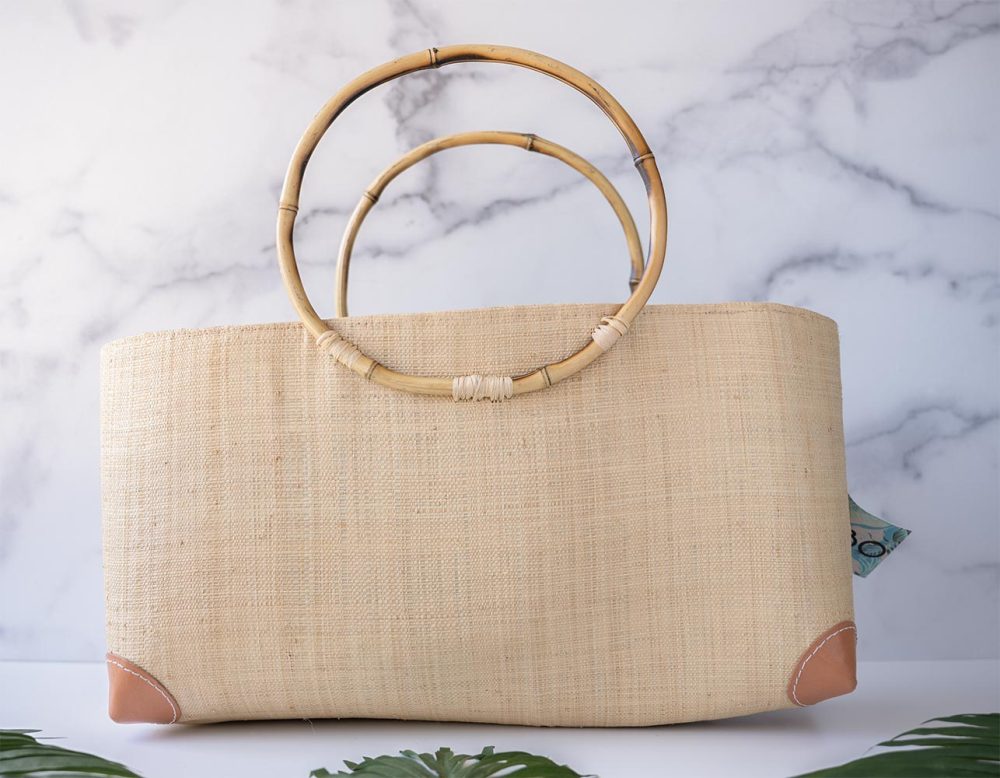Shebobo Bebe Straw Bag with Bamboo Handles against a clean white and marble background with palm leaves