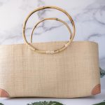 Shebobo Bebe Straw Bag with Bamboo Handles against a clean white and marble background with palm leaves