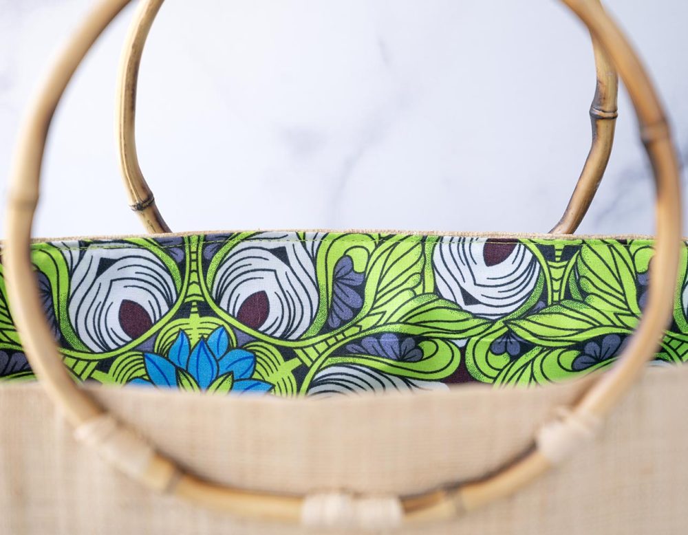 Top Open View of the of the Shebobo Bebe Straw Bag with Bamboo Handles against a clean white and marble background with palm leaves