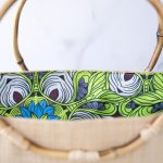 Top Open View of the of the Shebobo Bebe Straw Bag with Bamboo Handles against a clean white and marble background with palm leaves