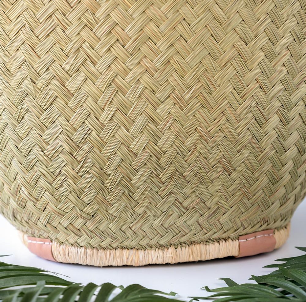 Closeup bottom view of the Aravola Round Basket by Shebobo on a clean white and marble background with palm leaves