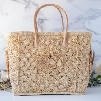 The Big Flower Crochet Basket by Shebobo on a clean white and marble background with palm leaves