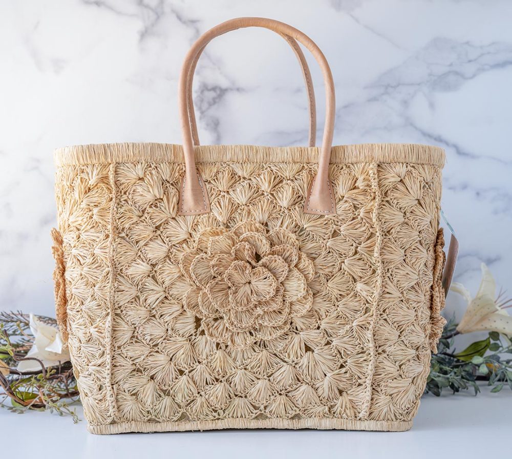 The Big Flower Crochet Basket by Shebobo on a clean white and marble background with palm leaves