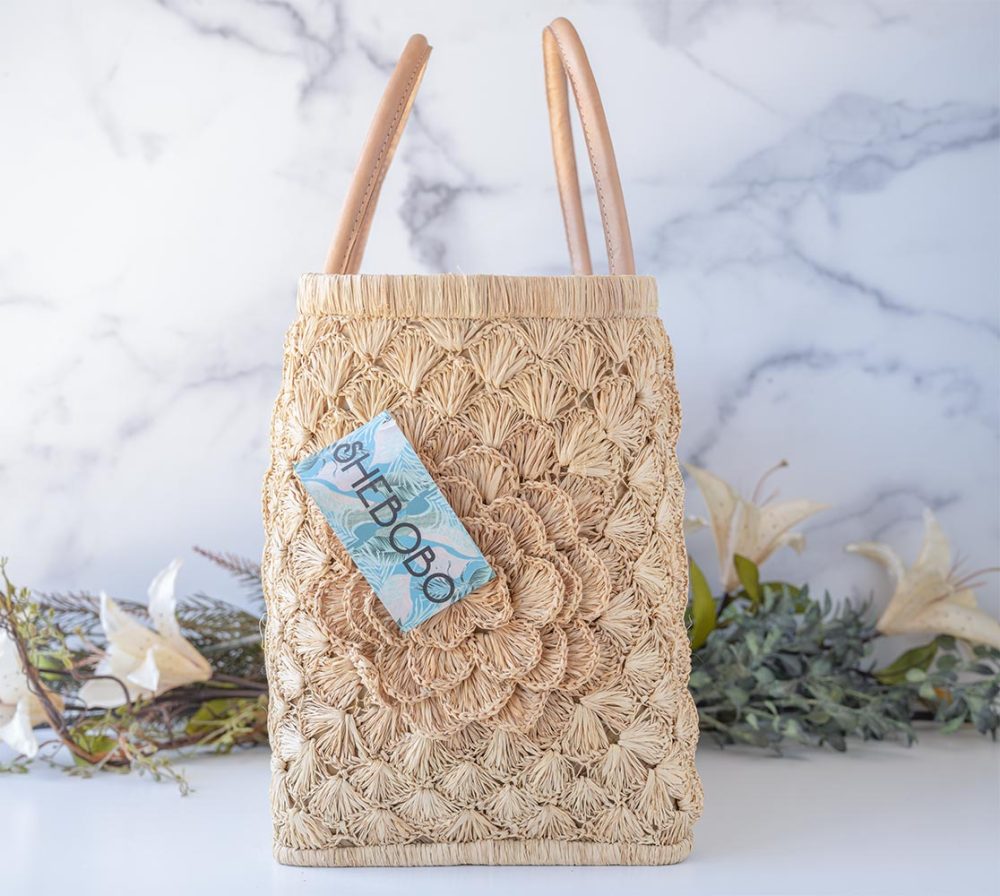 Side View of the The Big Flower Crochet Basket by Shebobo on a clean white and marble background with palm leaves