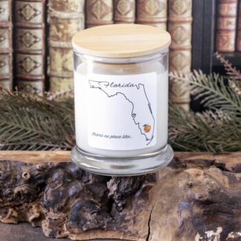 Front view of the State of Florida candle by Live Young Candle Co on a piece of wood with the bamboo lid on and against a rustic background