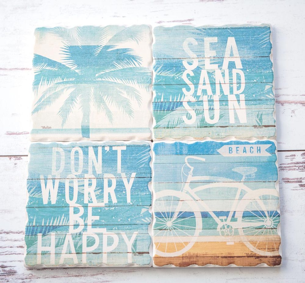 CounterArt & Highland Home Beachscapes coaster set sitting side by side on a white rustic wood background