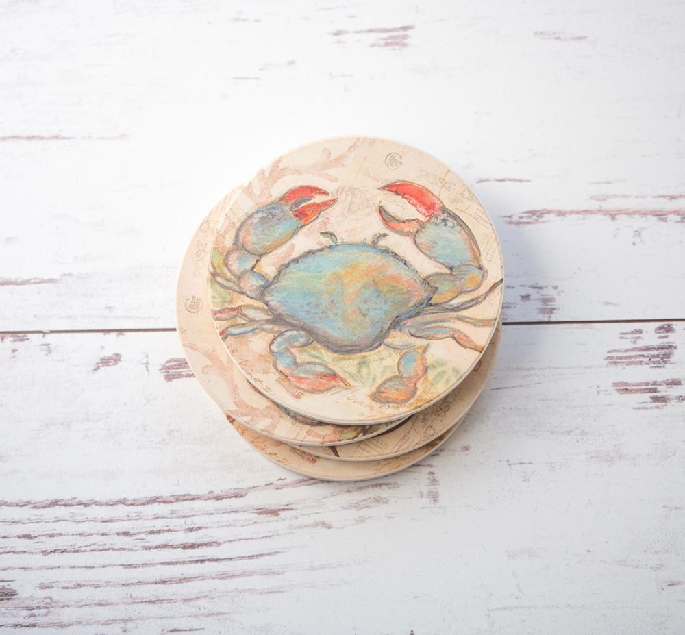 CounterArt & Highland Home Seaside Blue Crab coaster set of 4 stacked with colorful blue crab and sitting on top of a white rustic wood background