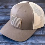Right Angle View of the RANGE LEather American Flag hat in Brown & Khaki on a rustic dark wood background