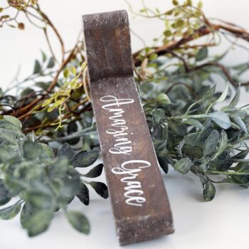 Joshua Jar Amazing Grace Rustic Wooden cross on a clean White Background With Greenery Around it