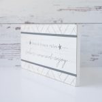 Angled View of the Beach House Rules Wooden Accent Sign by Gia Roma Against a Rustic Wooden Backdrop