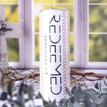 Redeemed Ephesians Skinny Tumbler by Emma K Designs in Front of a Kitchen Window Background with Greenery in Front and Behind the TUmbler