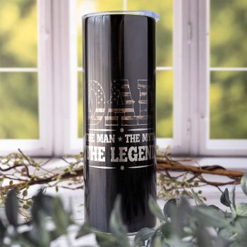Emma K Designs Dad - The Man, the Myth, the Legend Camo American Flag Skinny Tumbler in Front of a Kitchen Window Background with Greenery Behind it