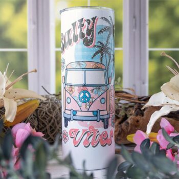 Salty Vibes Skinny Tumbler by Emma K Designs Against a Kitchen Window with Flowers on Both Sides