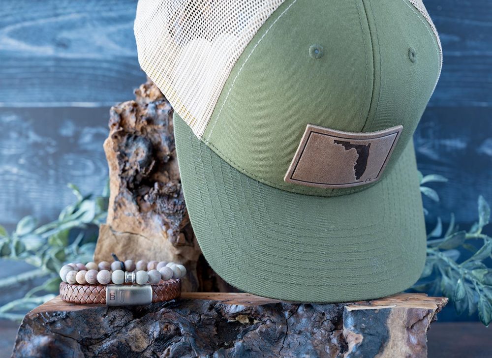 Men's Sunsational Set of the State of Florida RANGE LEather Hat in Moss & Khaki with the Steel & Barnett Matt Rainbow Beads Bracelet and Caramel Cornall Leather Bracelet on wood and a Rustic Background with Greenery