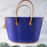 Back View of the American Flag Raffia Tote Bag by Shebobo Against a Marble and Clean White Background with Palm Leaves