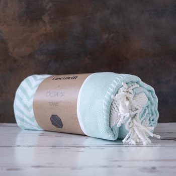 Angled View of the Case + Drift Octavia Turkish Towel in Mint on and against a white wood and rustic backdrop