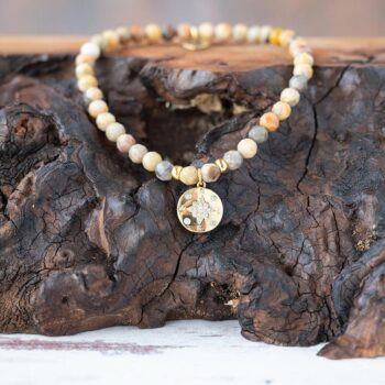Lenny & Eva Wanderlust Compass Bracelet resting on a piece of wood with a rustic background