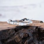 Lotus & Luna Song of Selene Moonstone bracelet laying on a piece of wood with white rustic wood background