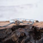 Back View of the Lotus & Luna Song of Selene Moonstone bracelet laying on a piece of wood with white rustic wood background