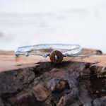 Back View of the Lotus & Luna When the Stars Align Moonstone bracelet laying on a piece of wood with white rustic wood background