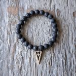 Top View of the VB&CO Designs Lava Bead Bracelet with Heart Charm on a Rustic Piece of Wood