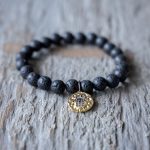 Closeup Front View of the VB&CO Designs Lava Bead Bracelet with Hamsa Charm on a Rustic Piece of Wood