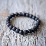 Closeup Back View of the VB&CO Designs Lava Bead Bracelet with Hamsa Charm on a Rustic Piece of Wood