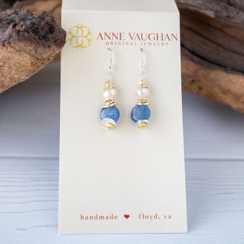 Anne Vaughn Designs Seaside Pearl Kyanite Earrings with Branded Tag Against a Rustic Piece of Wood