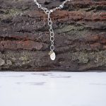 Back Closeup View of the Lakeside Patina Dragonfly Necklace by Anne Vaughn Designs on a Rustic Background
