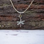 Front Closeup View of the Lakeside Patina Dragonfly Necklace by Anne Vaughn Designs on a Rustic Background