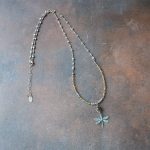 Top View of the Top View of the Lakeside Patina Dragonfly Necklace by Anne Vaughn Designs on a Dark Piece of Wood