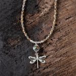 Top View of the Lakeside Patina Dragonfly Necklace by Anne Vaughn Designs on a Dark Piece of Wood