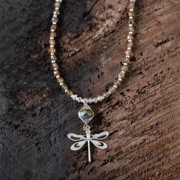 Top View of the Lakeside Patina Dragonfly Necklace by Anne Vaughn Designs on a Dark Piece of Wood