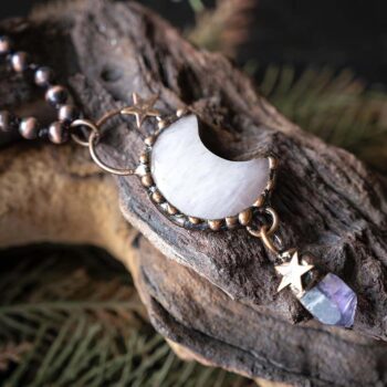Top Close up View of the Moon Charm and Pendant of the VB&CO Designs Luna Moon Boho Necklace laying on a piece of wood on a rustic background