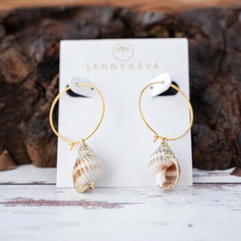 Lenny & Eva Coastal Seashell Earrings resting against a piece of wood with a white rustic wood background