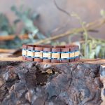 The men's two coasts liatris wooden bracelet by Nordic Wood on a piece of wood with rustic background and greenery