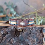 Back view of the men's two coasts liatris wooden bracelet by Nordic Wood on a piece of wood with rustic background and greenery
