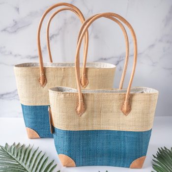 Perfect pairing of the Shebobo Trinidad Two Tone Straw Basket Bag in the color Aqua against a white and marble backdrop with palm leaves