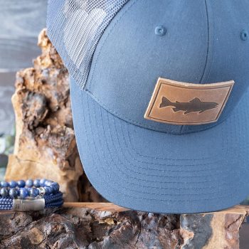 Two Shore Sunsational Set Collection of the Trout Hat in Navy and the Rope Lake Bracelet and Beaded bracelet in Navy on Wood and Against Rustic Background