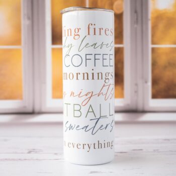 Front View of the All Things Fall Skinny Tumbler Against a Fall Scene Window and on Rustic Wood