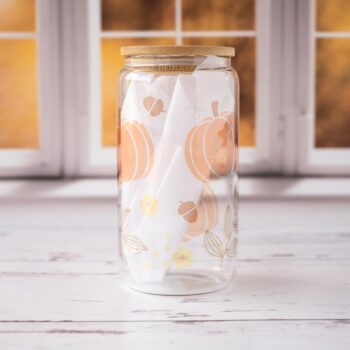 Front View of the Pumpkins Glass Tumbler by Emma K Designs against a Fall setting window and on rustic white wood.