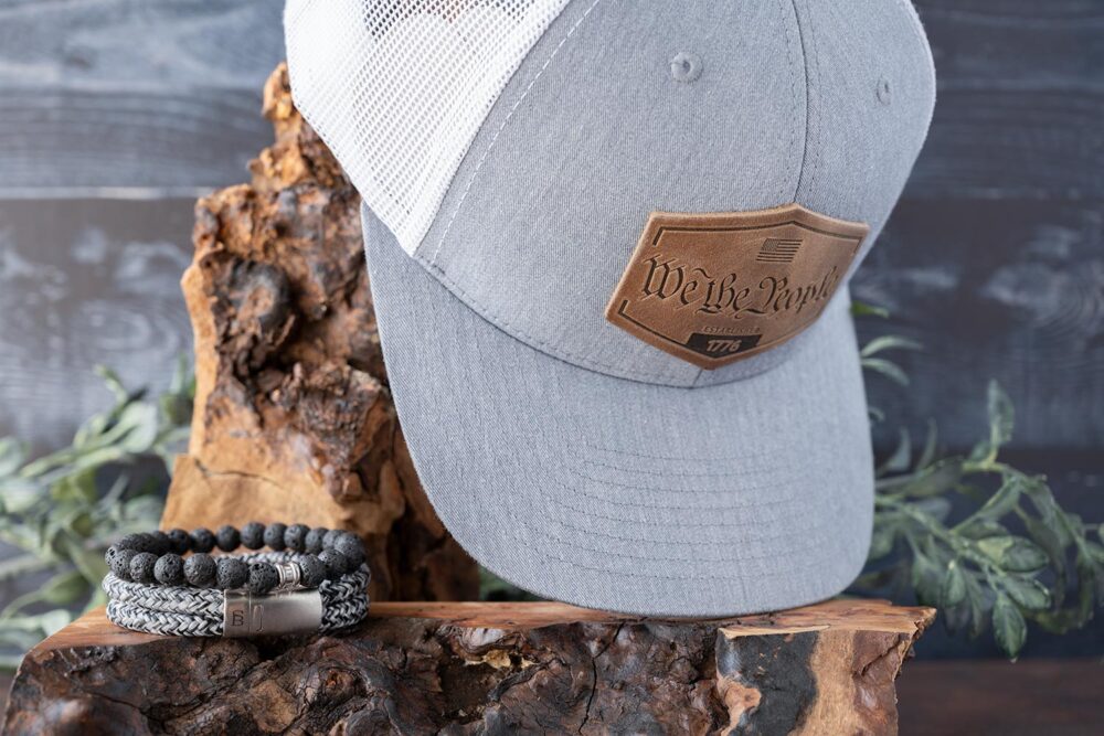 Dark to Light Collection of the RANGE Leather America Established Hat with the pairing of the Steel & Barnett Stones Beaded bracelet and Rope Lake bracelet on Wood and Dark Wood Background