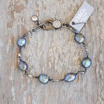 Top view of the Coastal Beach womens' peacock pearl bracelet on a distressed piece of brown wood