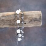 Side dangling view of the Sandy Shores pearl bracelet on a rustic brown piece of driftwood