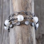 Top dangling view of the Sandy Shores pearl bracelet on a rustic brown piece of driftwood