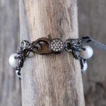Top dangling clasp view of the Sandy Shores pearl bracelet on a rustic brown piece of driftwood