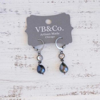 Top view of the Coastal Beach womens' peacock pearl earrings on a distressed piece of white wood