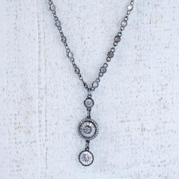 Front angle view of the crystal carriage necklace on top of a white rustic piece of wood