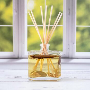Front view of the Andaluca Lemon Zest Botanical Reed Diffuser on a rustic piece of wood in front of a Spring window backdrop