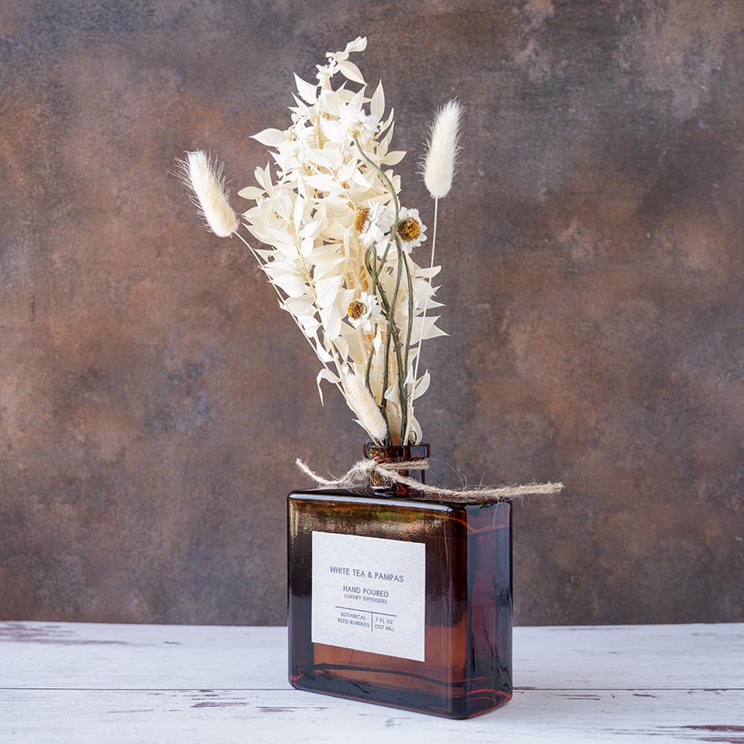 Left angle view of the White Tea & Pampas Bouquet Reed Diffuser on a rustic and white wood background
